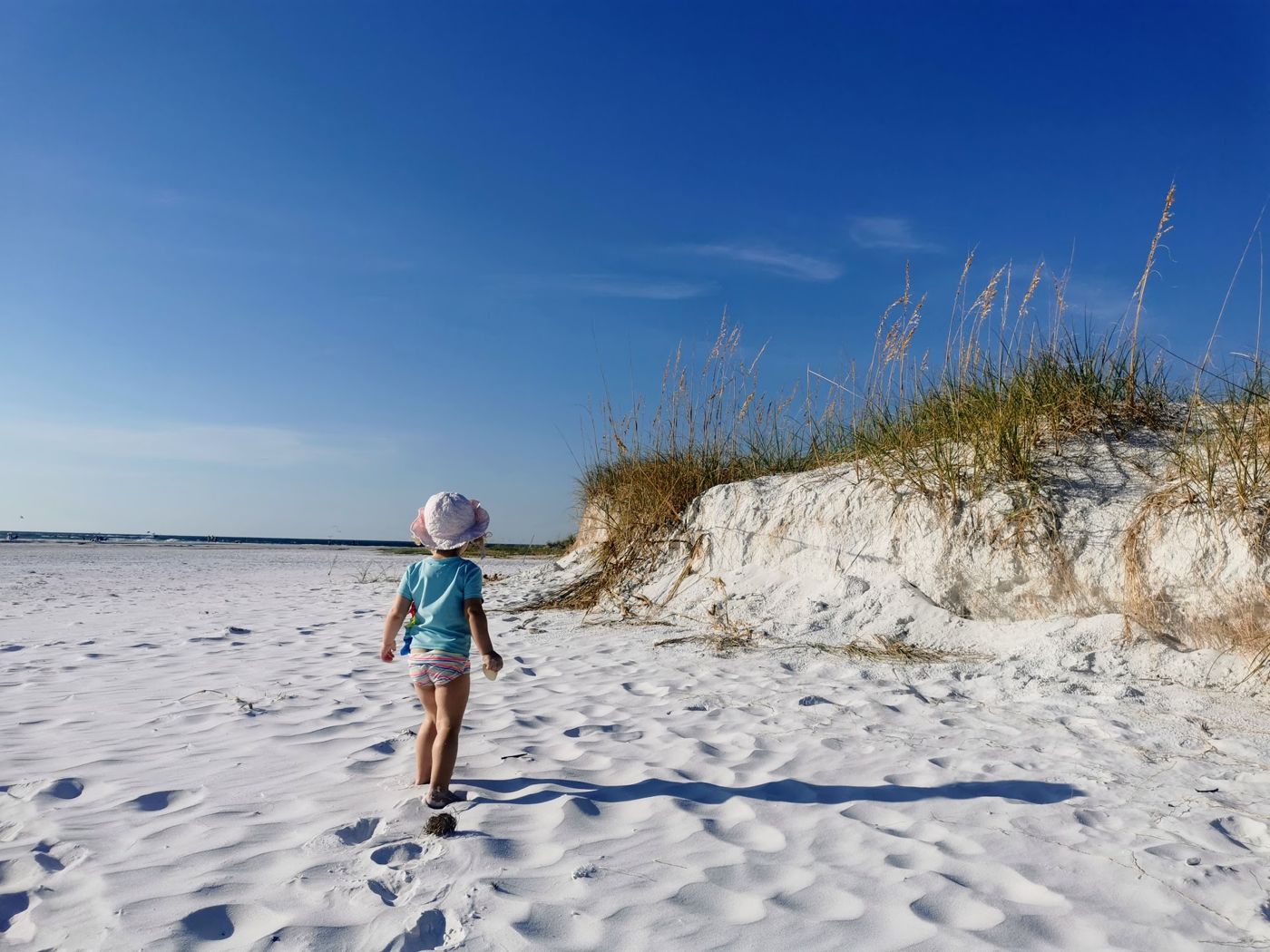 Kind am weissen Sandstrand vor einer Düne mit Strandhafer